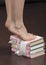 Caucasian female feet standing tiptoe on stack of books closeup