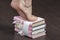 Caucasian female feet standing tiptoe on stack of books closeup