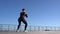 Caucasian female fitness model performing squat jumps exercise outdoor at sea promenade