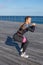 Caucasian female fitness model performing squat with a rubber band exercise outdoor at a sea promenade