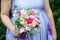 Caucasian female guest or bridesmaid wearing a lilac summer dress which shows a lovely baby bump and holding a wedding bouquet