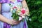 Caucasian female guest or bridesmaid wearing a lilac summer dress which shows a lovely baby bump and holding a wedding bouquet