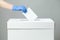 Caucasian female hand wearing blue protective latex rubber glove placing ballot paper in vote box