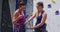 Caucasian female instructor showing woman how to knot a rope to a harness at indoor climbing wall