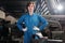 A Caucasian female worker looks at camera and akimbo in a mechanical factory