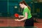 A Caucasian fifteen-year-old brunette girl makes a ball pitch in table tennis . ping pong