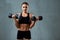 Caucasian fitnesswoman training with dumbbells.