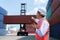 Caucasian foreman man is using walkie talkie to command his workers with crane lifting container in background in container depot