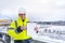 Caucasian foreman in white working helmet and a yellow jacket holds clipboard and pointing finger to empty paper sheet