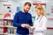 Caucasian friendly pharmacist has a nice conversation with a client, helps to find a medication