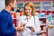 Caucasian friendly pharmacist has a nice conversation with a client, helps to find a medication