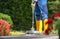 Caucasian Garden Keeper in His 40s Washing Concrete Bricks Driveway Using a Modern Pressure Washer