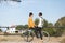 Caucasian girl with African boy on the same bike with a park with trees in the background. Interracial concept