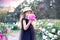 Caucasian girl in a black dress and a hat with a pink peony near her face