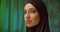 Caucasian girl black hijab neon make-up portrait light night green background