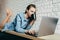 Caucasian girl in a blue shirt and long hair lies and drinks coffee while working on a computer, chatting with friends, listens to