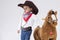 Caucasian Girl in Cowgirl Clothing Posing With Symbolic Plush Horse Against White.