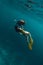 Caucasian girl freediving underwater with lovely turtle in blue sea