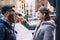 Caucasian girl gives a piece of pizza to a guy with a beard and glasses on a city street