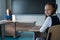 Caucasian girl and her teacher in the classroom. Schoolgirl turns around and looks at the camera.