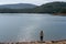Caucasian girl looking at the lake water of Apartadura dam with mountains with trees landscape in Alentejo, Portugal