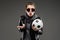 Caucasian girl with rough facial features in a black jacket holds soccer ball isolated on black background