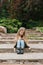 Caucasian girl of seven years old sits on stone steps in a park and communicates online with friends on a smartphone