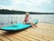 Caucasian girl sitting on paddle surf board by lake river