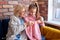 Caucasian girl sitting together with senior grandmother, learning how to knit