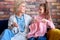 Caucasian girl sitting together with senior grandmother, learning how to knit