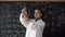 caucasian girl student in a white coat at a biology lesson reads a book takes a test tube and a pepper plant studies