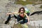 Caucasian girl in sunglass with red hair climbing at stones in mountain