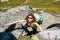 Caucasian girl in sunglass with red hair climbing on the stones in mountain