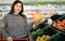 A Caucasian girl in a supermarket in the fruit department stands and holds a large pomelo in her hand. Citrus fruits and health