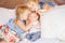 Caucasian girls sisters holding kissing little baby, sitting on bed