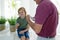 Caucasian grandfather in bathroom brushing teeth with smiling grandson sitting beside basin