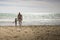 Caucasian grandfather and granddaughter walking on the beach. Vertical