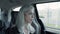 Caucasian gray-haired woman sitting in backseat of moving car.