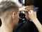 Caucasian hairdresser with razor shave the boy in the Barber shop