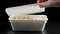 caucasian hand opening rectangular styrofoam container with hot cooked instant noodles