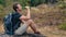 Caucasian hiker hiking on trail to mountain peak and resting on rock for his success