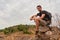 Caucasian hiker hiking on trail to mountain peak and resting on rock for his success