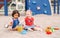 Caucasian and hispanic latin babies children sitting in sandbox playing with plastic colorful toys