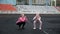 Caucasian identical pretty twins in sportswear do squats exercise at stadium