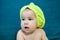 Caucasian infant child portrait after bath, yellow towel on head, blue background