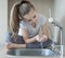 Caucasian little girl drinking fresh water in kitchen at home. Thirsty baby. Hands open for drinking tap water. Healthy Eating and