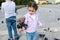 Caucasian little girl looking at a pigeon sitting on her arm, while feeding flock of flying doves in city park