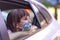 Caucasian little girl  wearing mask looking out of the open window of a car.