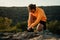 Caucasian male athlete stopping to take a break tying shoe lace while on outdoor run in wilderness