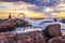 Caucasian male on the beach at sunset fishing from the rocks on the shoreline, with Table Mountain and Cape Town coastline